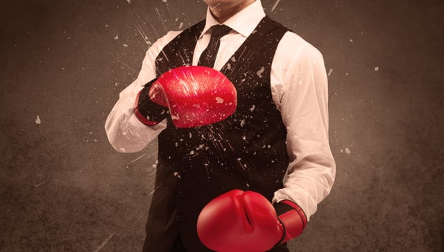 A strong sales person breaking something into pieces with red boxing gloves concept illustrated with glowing residue flying in the air.